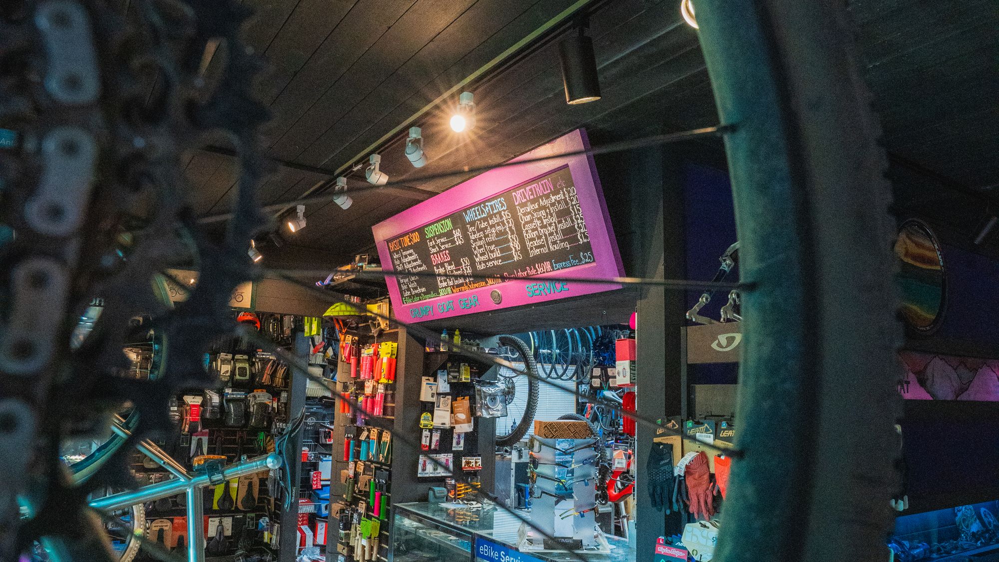 Parts and accessories on the shop floor, framed through a bike wheel